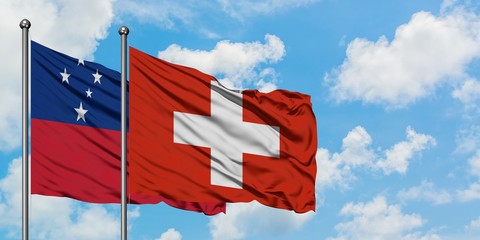 Samoa and Switzerland flag waving in the wind against white cloudy blue sky together. Diplomacy...
