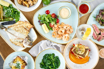 Plates seafood BBQ with garnish. Variety of dishes on the table. Restaurant menu.