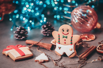 Obraz na płótnie Canvas Christmas festive composition gingerbread man, decoration, cinnamon on a background of bokeh lights cyan color, toned. Selective focus.