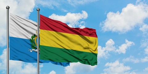 San Marino and Bolivia flag waving in the wind against white cloudy blue sky together. Diplomacy concept, international relations.