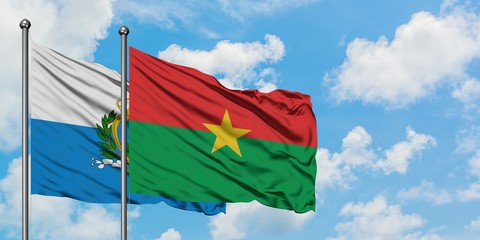San Marino and Burkina Faso flag waving in the wind against white cloudy blue sky together. Diplomacy concept, international relations.