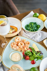 Fototapeta na wymiar Dish shrimp with arugula and lemon. BBQ seafood. Restaurant menu. Variety of dishes on the table. Restaurant menu.