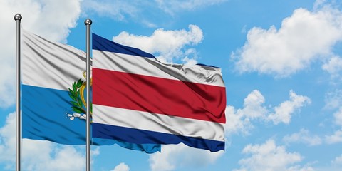San Marino and Costa Rica flag waving in the wind against white cloudy blue sky together. Diplomacy concept, international relations.