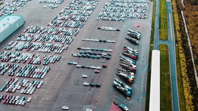 cars and transporting trucks stand on outdoor parking lot