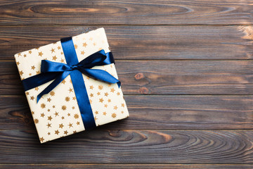 Beautiful gift box with a colored bow on the dark wooden table. Top view with copy space for you...