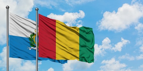 San Marino and Guinea flag waving in the wind against white cloudy blue sky together. Diplomacy concept, international relations.