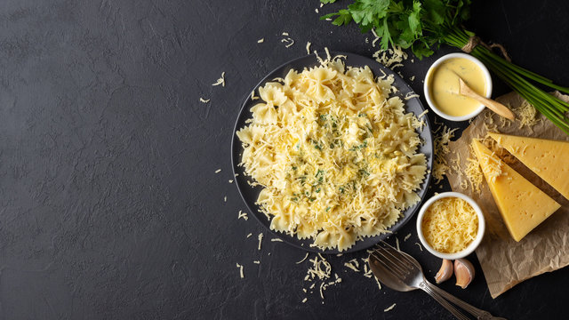 Cooked italian farfalle pasta (bow-tie or butterfly) with with sauce and grated cheese. Above view with copy space. Black background.