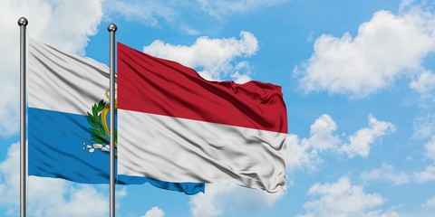 San Marino and Indonesia flag waving in the wind against white cloudy blue sky together. Diplomacy...