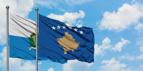San Marino and Kosovo flag waving in the wind against white cloudy blue sky together. Diplomacy...