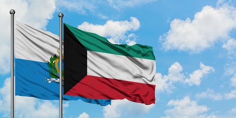 San Marino and Kuwait flag waving in the wind against white cloudy blue sky together. Diplomacy...