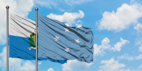 San Marino and Micronesia flag waving in the wind against white cloudy blue sky together. Diplomacy...