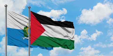 San Marino and Palestine flag waving in the wind against white cloudy blue sky together. Diplomacy concept, international relations.