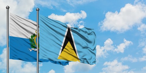 San Marino and Saint Lucia flag waving in the wind against white cloudy blue sky together. Diplomacy concept, international relations.