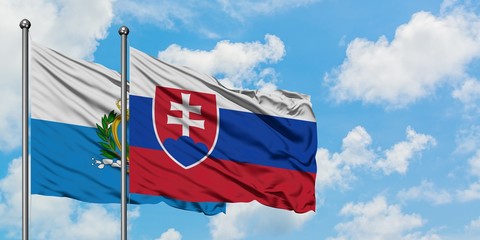San Marino and Slovakia flag waving in the wind against white cloudy blue sky together. Diplomacy concept, international relations.