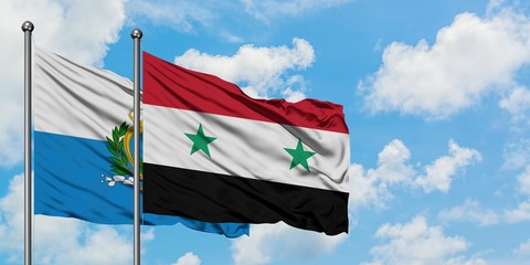San Marino and Syria flag waving in the wind against white cloudy blue sky together. Diplomacy...