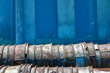 a stack of rusting galvanized buckets is turned on its side. Vintage grunge windows and doors are seen in the background.
