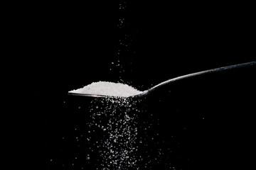 spoon of sugar on black background