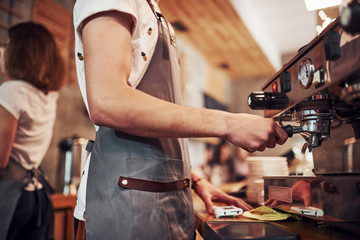 With machine. Two young cafe workers indoors. Conception of business and service