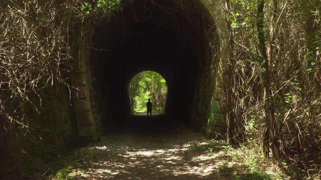 Approach of camera to man still in a tunnel