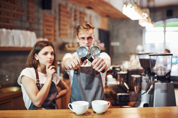 Front view. Two young cafe workers indoors. Conception of business and service
