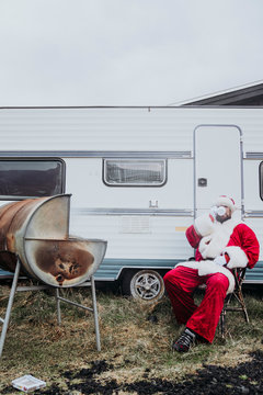 Santa Claus preparing a barbecue in front of a camper