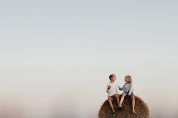 Two kids sitting on the haystack