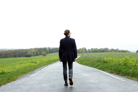 Rear view of a senior woman taking a walk on a country road