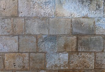 old grey rectangular stone wall with many rough edges