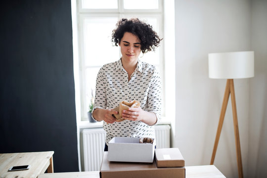 Young woman wrapping a product at table