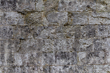 old grey rectangular stone wall with many rough edges