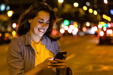 Young woman using smartphone in the city at night