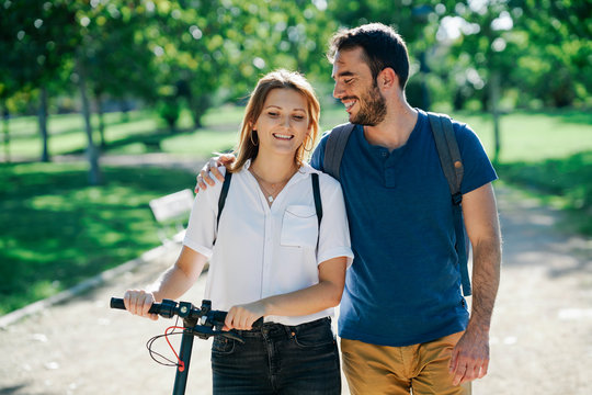 Happy couple with electric scooter in a city park