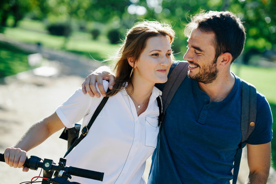 Happy couple with electric scooter in a city park