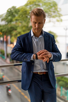 Young businessman checking the time on pedestrian bridge