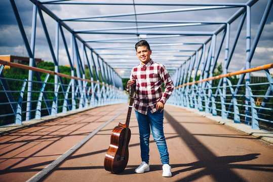 Gypsy boy with guitar on a bridge