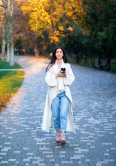 Fototapeta premium young female in white cardigan in the autumn park with black cup of coffee