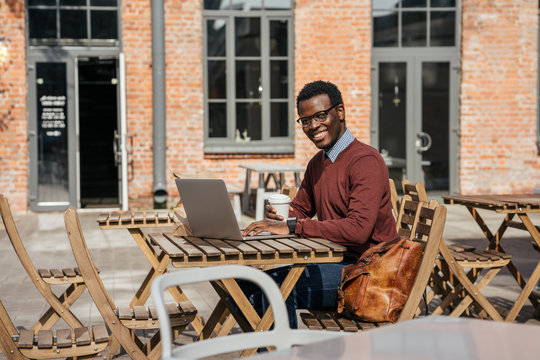 Young man using laptop in a coffee shop, drinking coffee