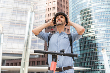 Man fastening the helmet before riding on electric scooter, Berlin, Germany