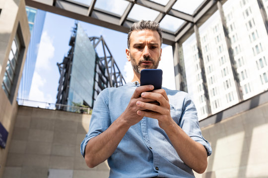 Serious businessman looking at the smartphone in the city, Berlin, Germany