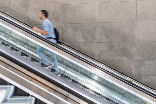 Businessman in a hurry walking up escalator in the city, Berlin, Germany