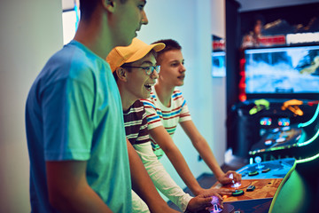 Teenage friends playing with a gaming machine in an amusement arcade