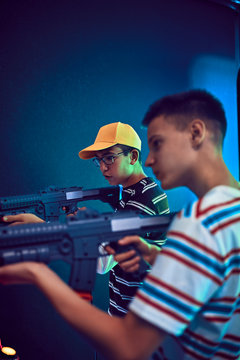 Teenage friends shooting with guns in an amusement arcade