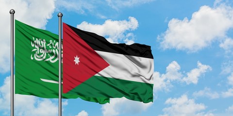 Saudi Arabia and Jordan flag waving in the wind against white cloudy blue sky together. Diplomacy concept, international relations.