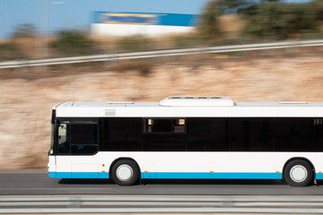 White bus moving fast along the street on a motion blurred background. Bus driving on freeway, motion blur. City bus on the street.