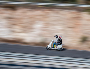 White motorcycle fast along the street on a motion blurred background. Moto driving on freeway, motion blur. Couple on motorcycle. 
