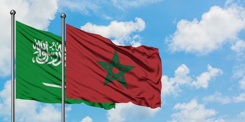 Saudi Arabia and Morocco flag waving in the wind against white cloudy blue sky together. Diplomacy...