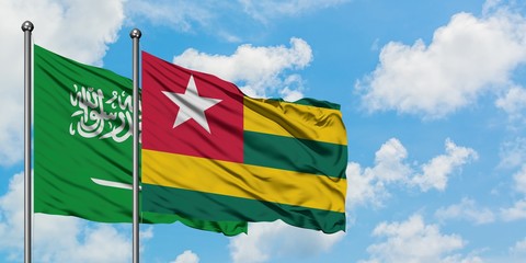 Saudi Arabia and Togo flag waving in the wind against white cloudy blue sky together. Diplomacy concept, international relations.