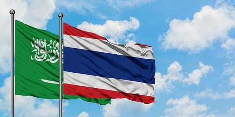 Saudi Arabia and Thailand flag waving in the wind against white cloudy blue sky together. Diplomacy concept, international relations.