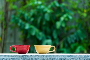 red and yellow ceramic coffee cup on marble table