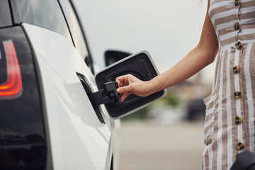 Woman on the electric cars charge station at daytime. Brand new vehicle